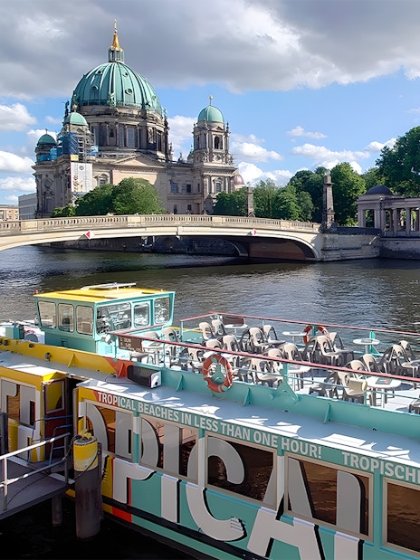 Sightseeing cruise boat on the Spree River with Berlin Cathedral in the background.