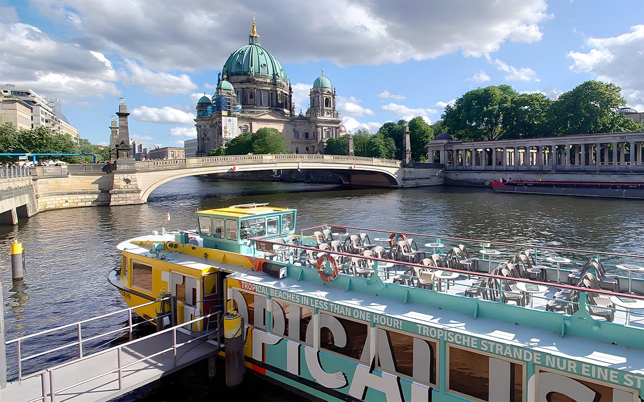 Sightseeing cruise boat on the Spree River with Berlin Cathedral in the background.