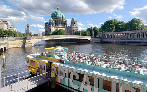 Sightseeing cruise boat on the Spree River with Berlin Cathedral in the background.