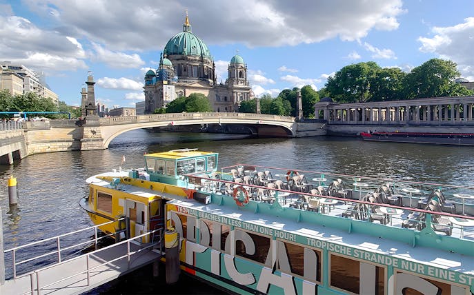 Sightseeing cruise boat on the Spree River with Berlin Cathedral in the background.