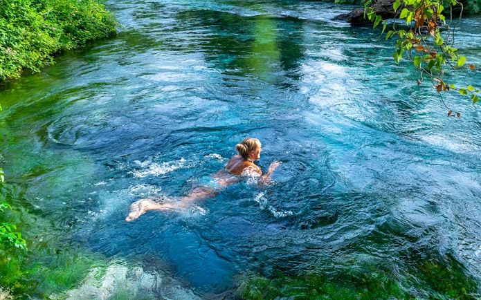 Tourist swimming in the Blue Eye waters, Albania.
