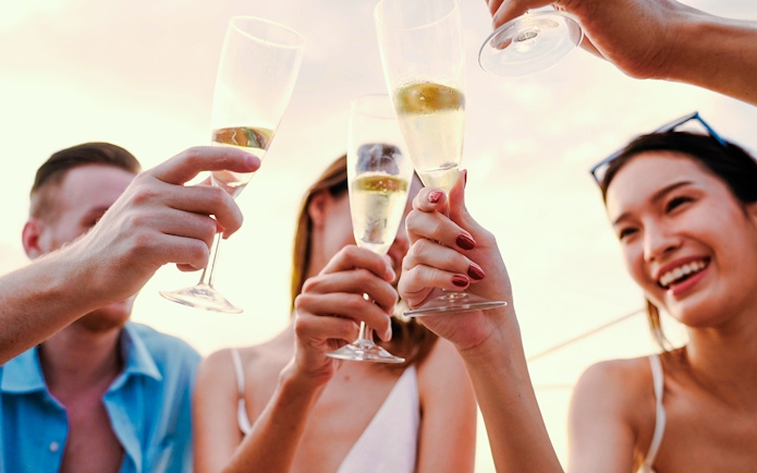 People toasting with sparkling wine on a sundowner cruise.