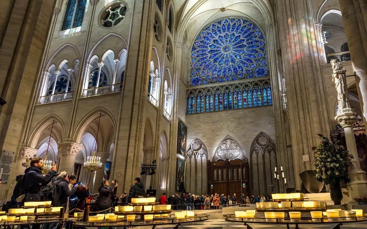Visitors inside Notre Dame Cathedral, Paris, viewing stained glass rose window.