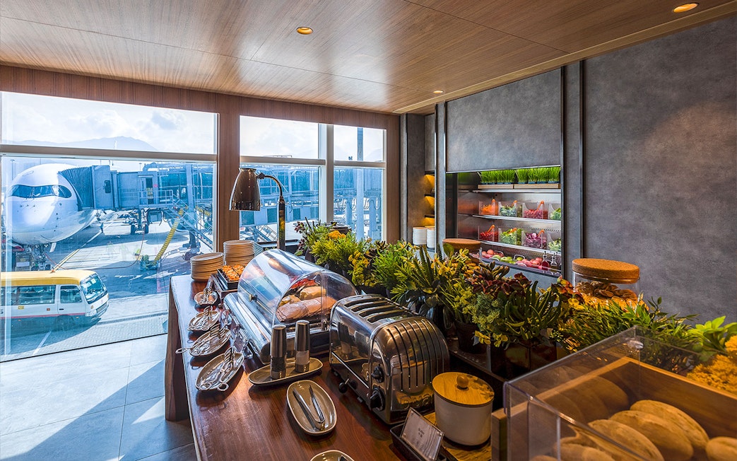 Plaza Premium Lounge buffet with view of airplane at airport terminal.