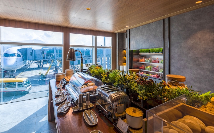 Plaza Premium Lounge buffet with view of airplane at airport terminal.