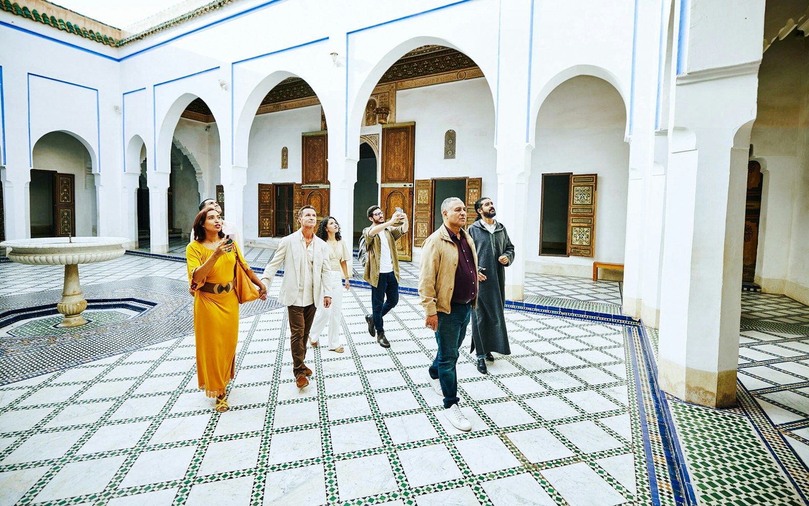 Tourists exploring the courtyard of Bahia Palace in Marrakech, Morocco.