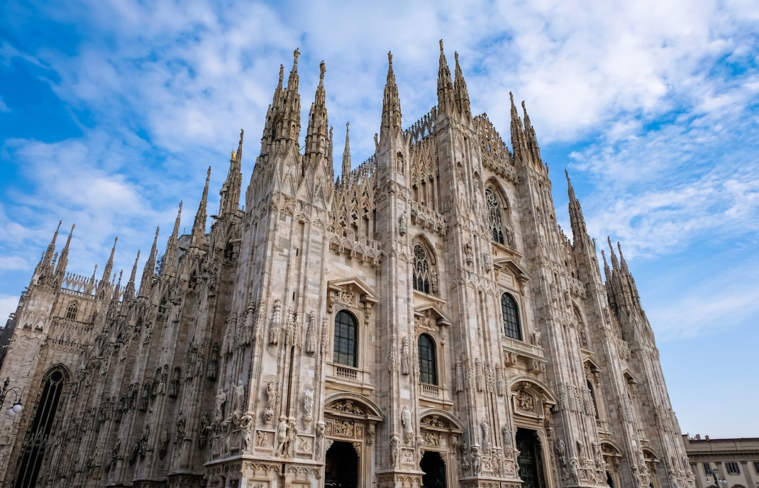 Duomo di Milano facade with spires under blue sky.