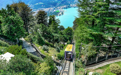 Funicular railway ascending through trees with Lake Como in the background, Italy.
