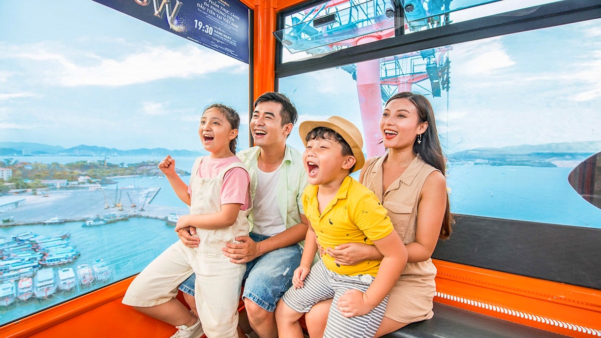 Family enjoying a cable car ride at Vinwonders, Nha Trang, Vietnam with ocean view.