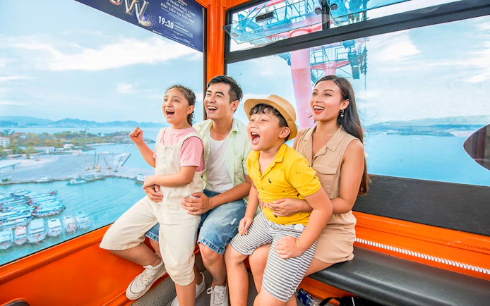Family enjoying a cable car ride at Vinwonders, Nha Trang, Vietnam with ocean view.