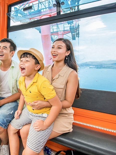 Family enjoying a cable car ride at Vinwonders, Nha Trang, Vietnam with ocean view.