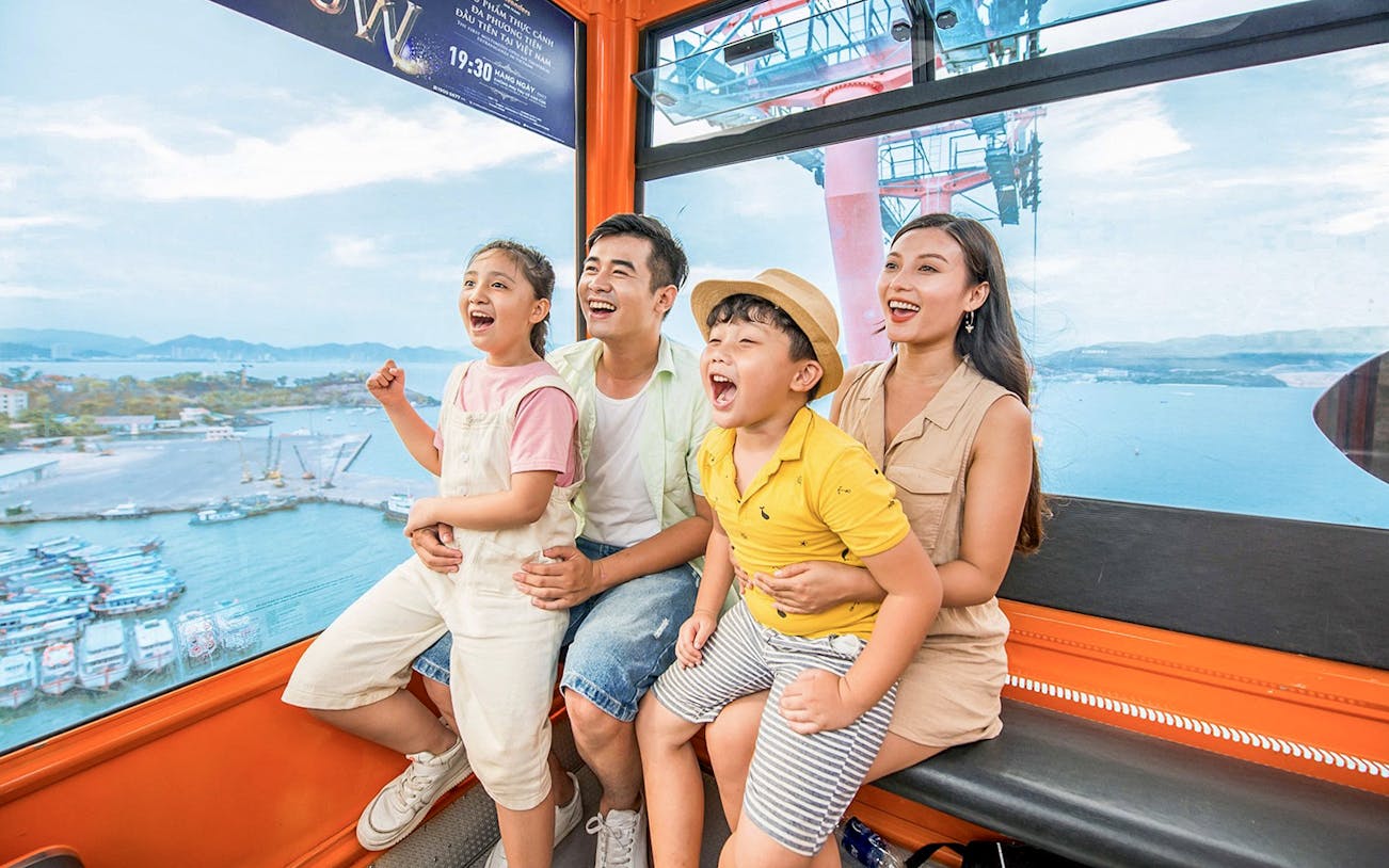 Family enjoying a cable car ride at Vinwonders, Nha Trang, Vietnam with ocean view.