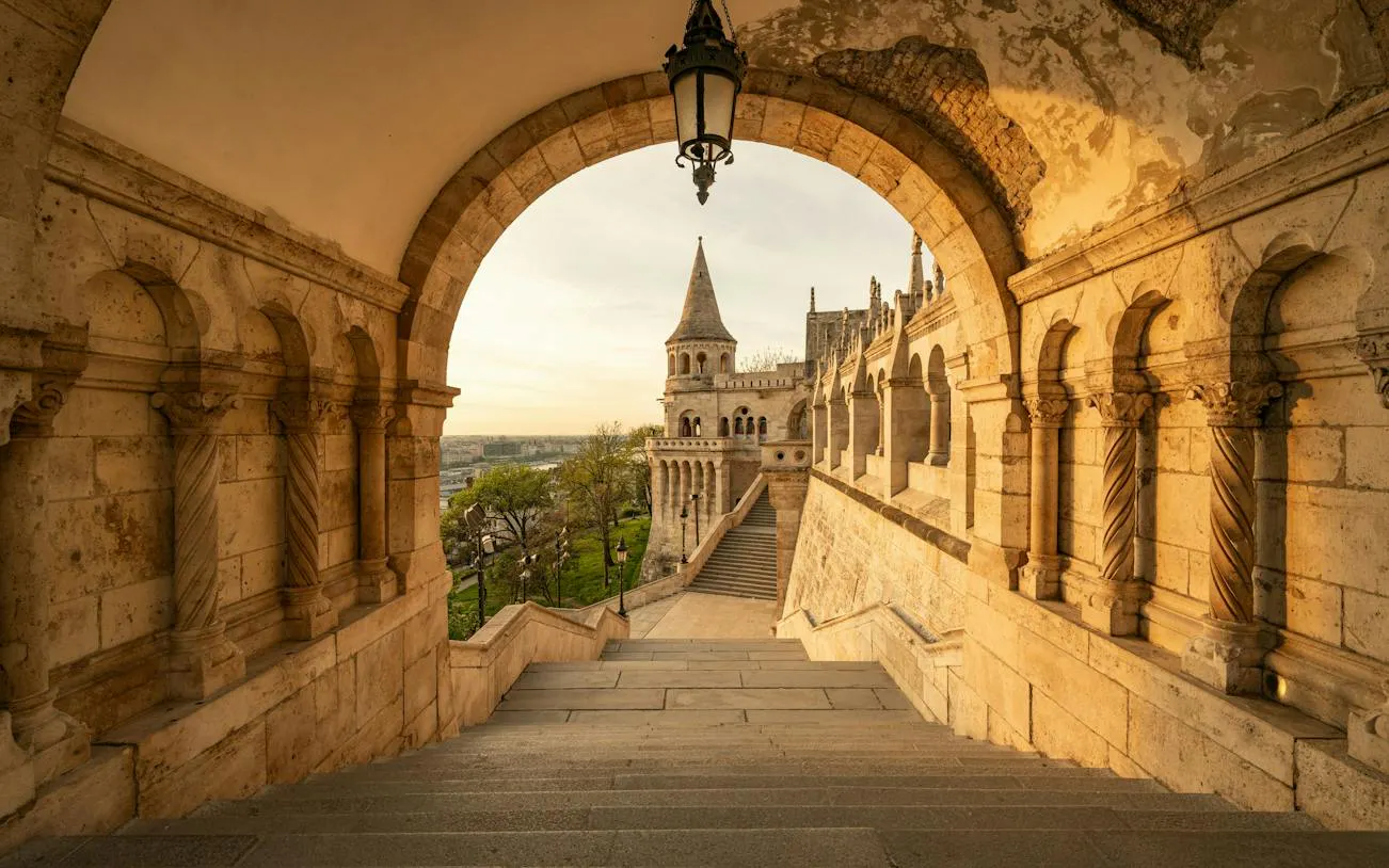 Fisherman's Bastion arches overlooking Budapest cityscape at sunset.