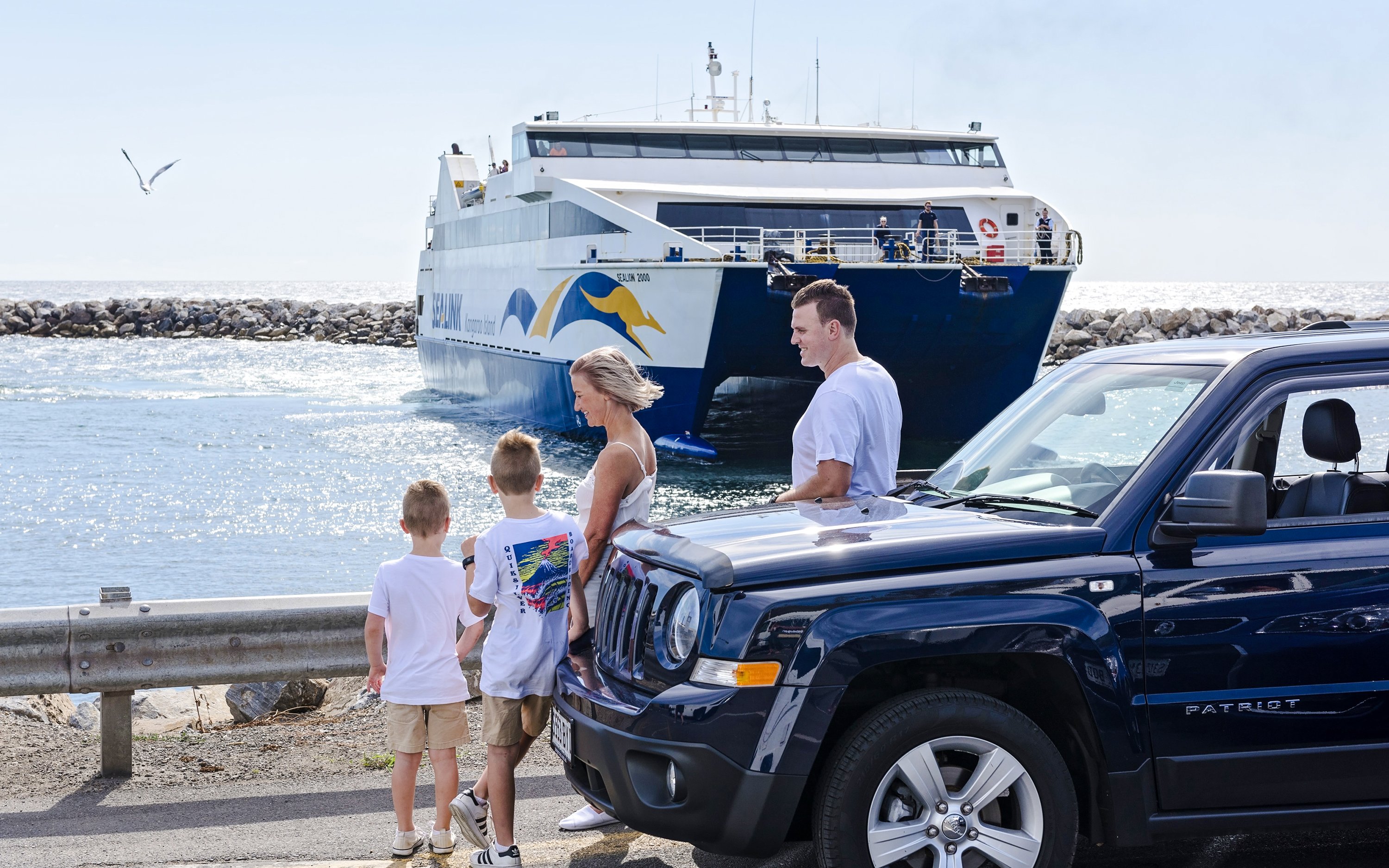 Family near car with ferry approaching Kangaroo Island.