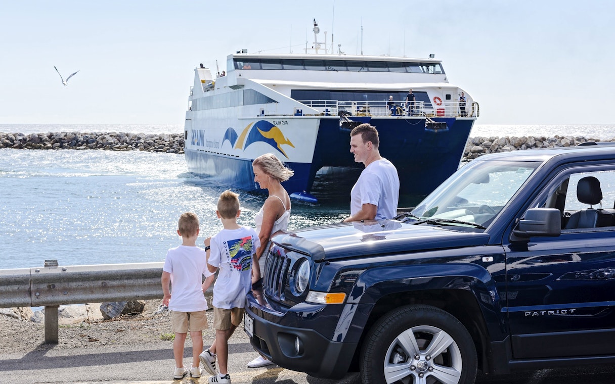 Family near car with ferry approaching Kangaroo Island.