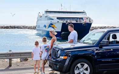 Family near car with ferry approaching Kangaroo Island.