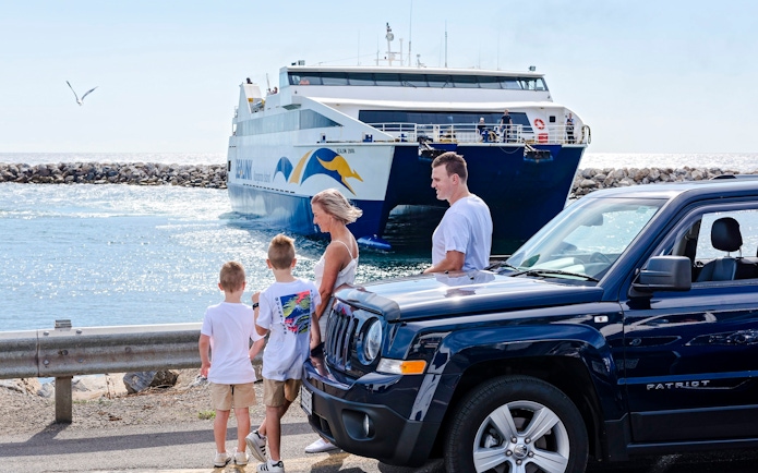 Family near car with ferry approaching Kangaroo Island.
