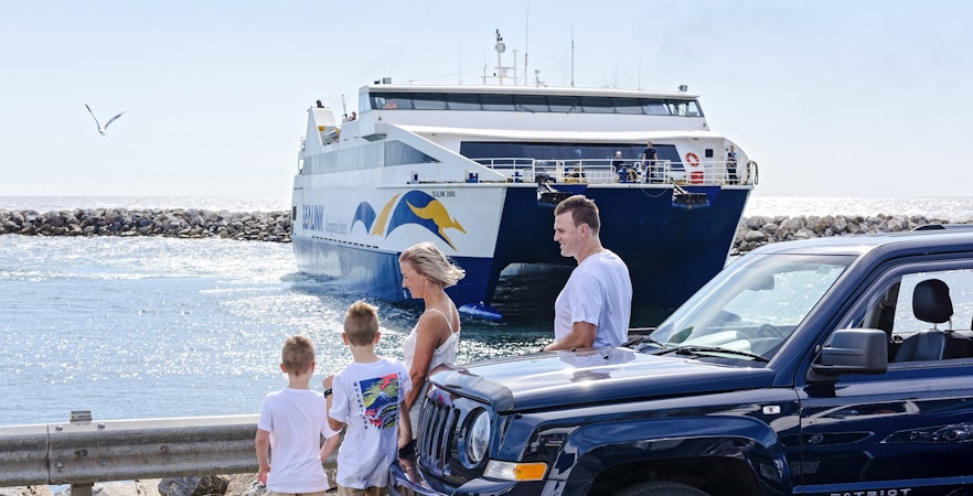 Family near car with ferry approaching Kangaroo Island.
