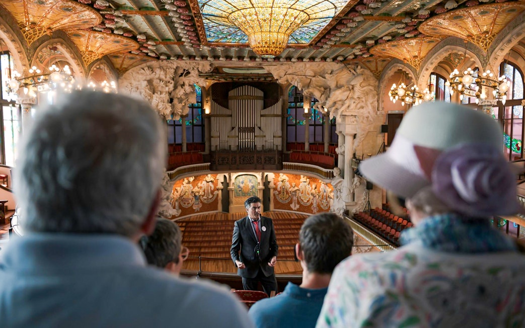 Tour guide speaking to visitors inside Palau de la Música Catalana, Barcelona.