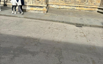 People walking along a historic stone building in York during a self-guided murder mystery tour.