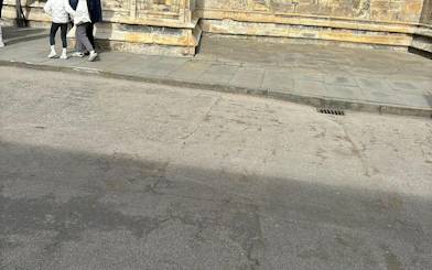 People walking along a historic stone building in York during a self-guided murder mystery tour.