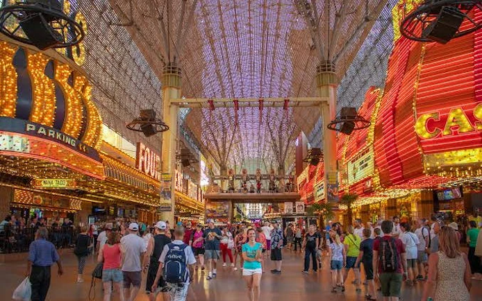 Downtown Las Vegas Fremont Street with crowds, neon lights, and casino signs.