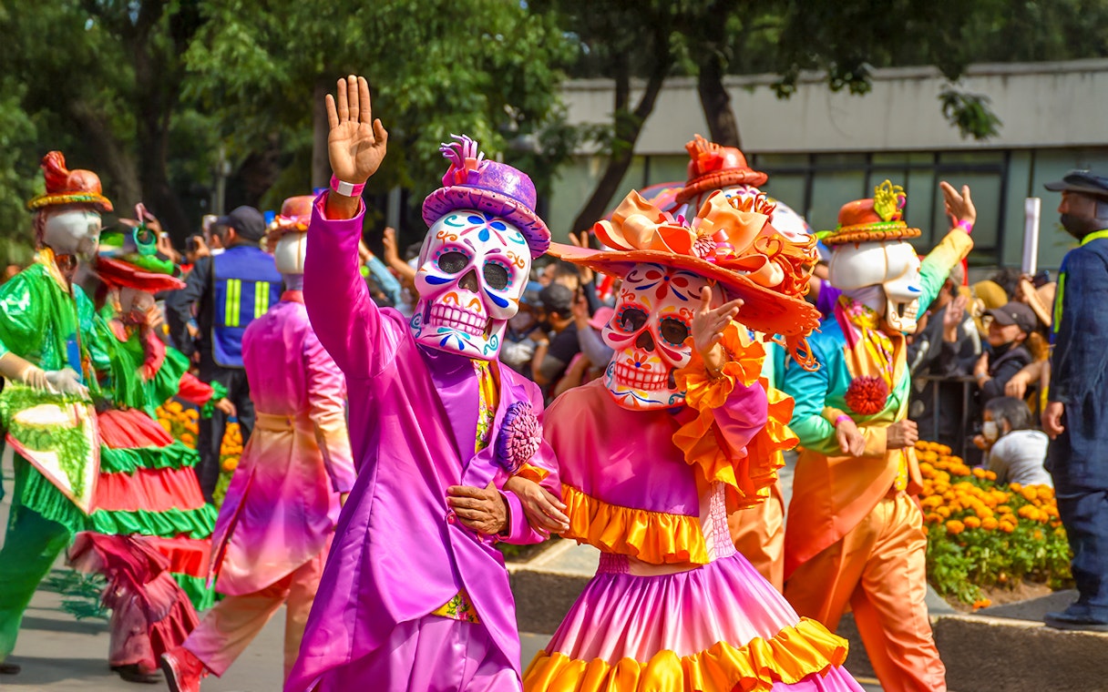 Participants in colorful costumes and skull masks at Day of the Dead parade, Mexico.