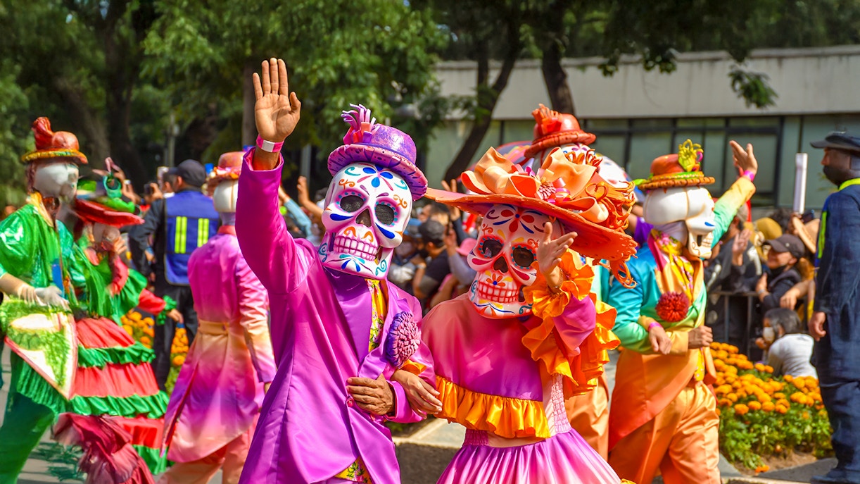 Participants in colorful costumes and skull masks at Day of the Dead parade, Mexico.