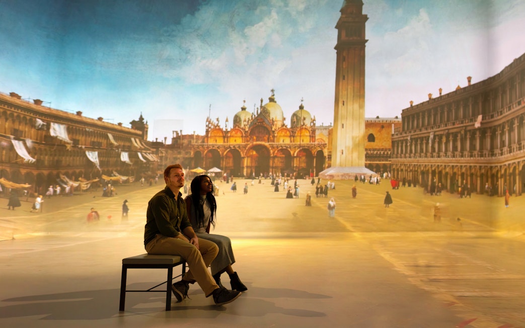 Tourists viewing a gallery exhibit featuring a historical cityscape.