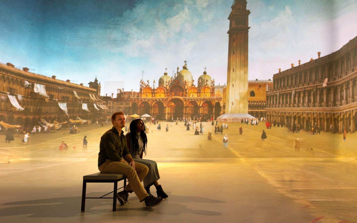 Tourists viewing a gallery exhibit featuring a historical cityscape.