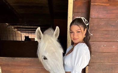 Woman with a white horse in a stable, Tuscany Horseback Ride and Winery Tour.