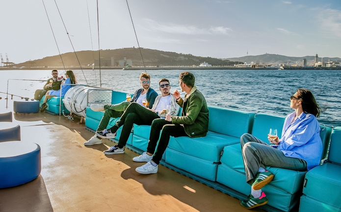 Tourists relaxing on a cruise in Barcelona with city skyline in the background.