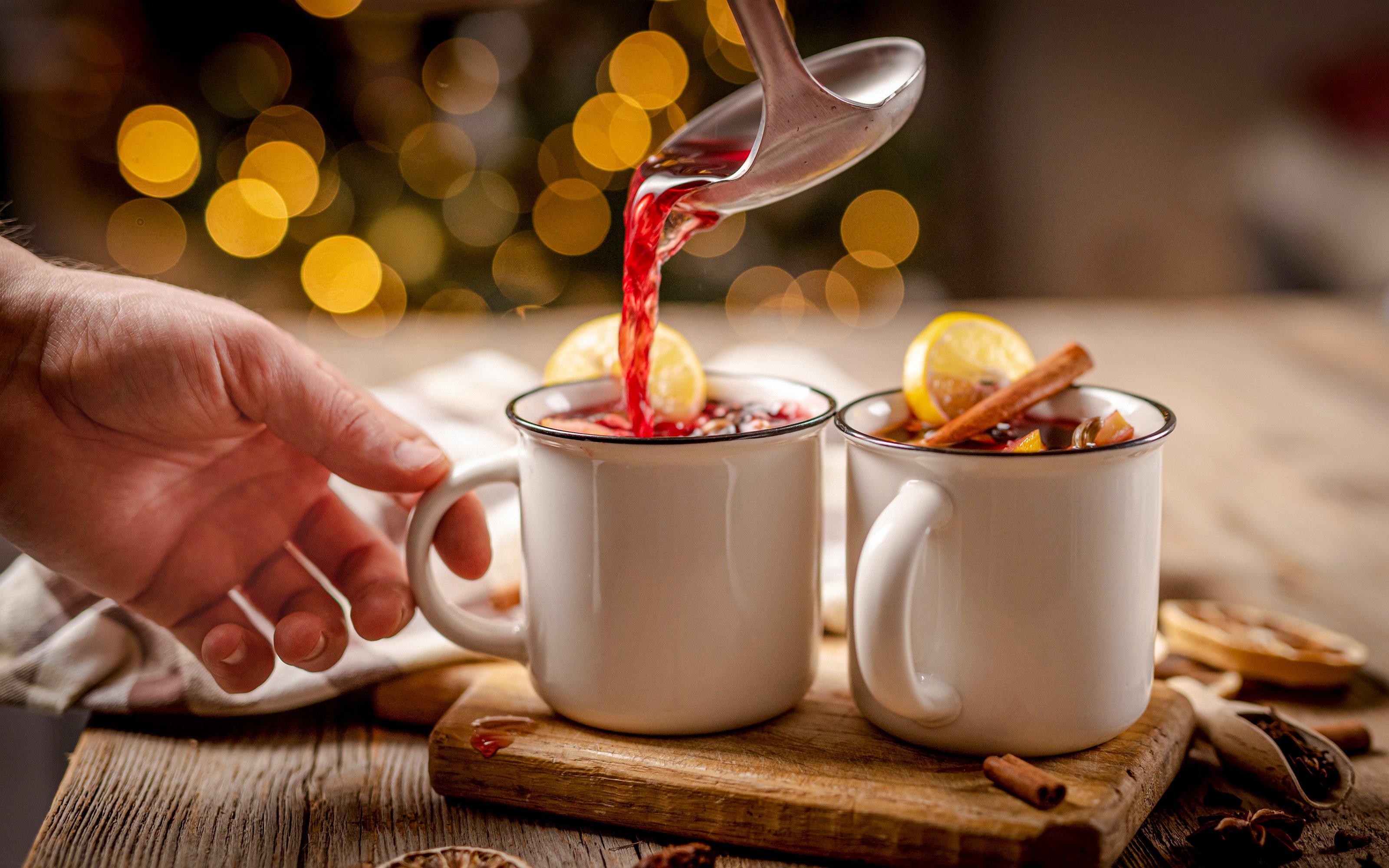 Pouring svařák into mugs with lemon and cinnamon, Prague Christmas market.