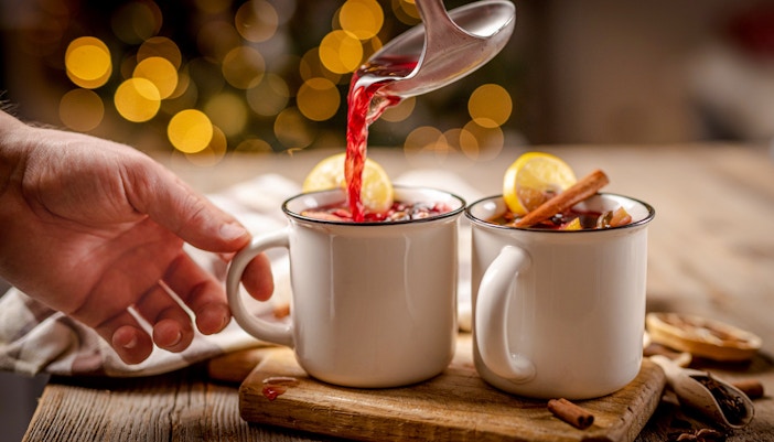Pouring svařák into mugs with lemon and cinnamon, Prague Christmas market.