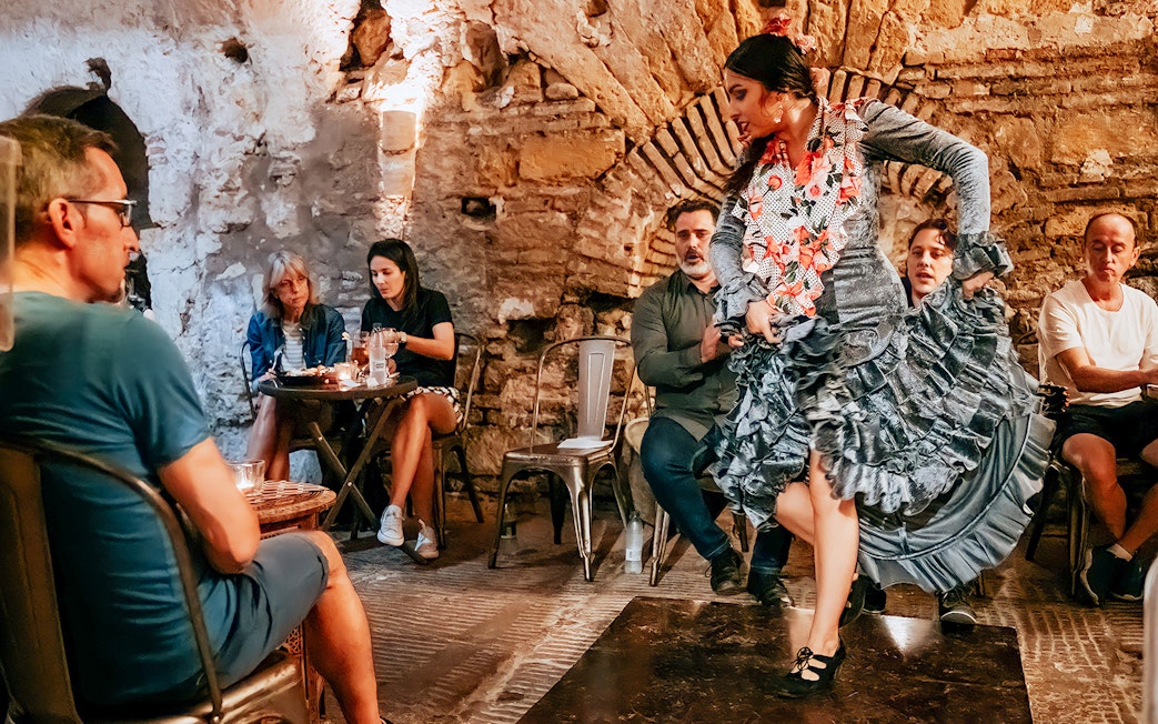 Flamenco dancer performing at Tablao en Baños Árabes de Santa María with audience seated nearby.
