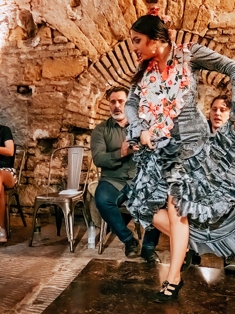 Flamenco dancer performing at Tablao en Baños Árabes de Santa María with audience seated nearby.
