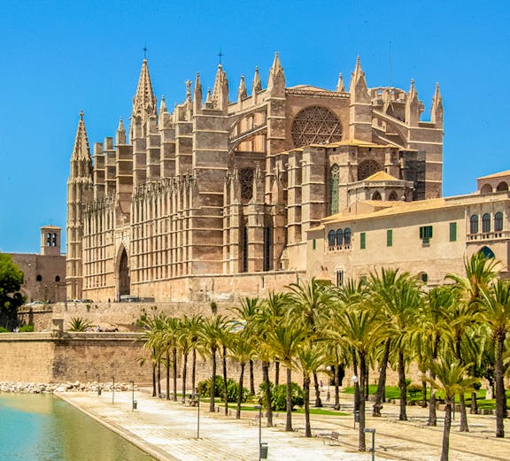 Mallorca Cathedral with palm trees and waterfront in Palma, Spain.