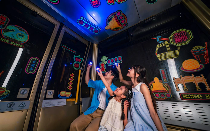 Family exploring illuminated illustrations inside Ngong Ping 360 cable car on Lantau Island.