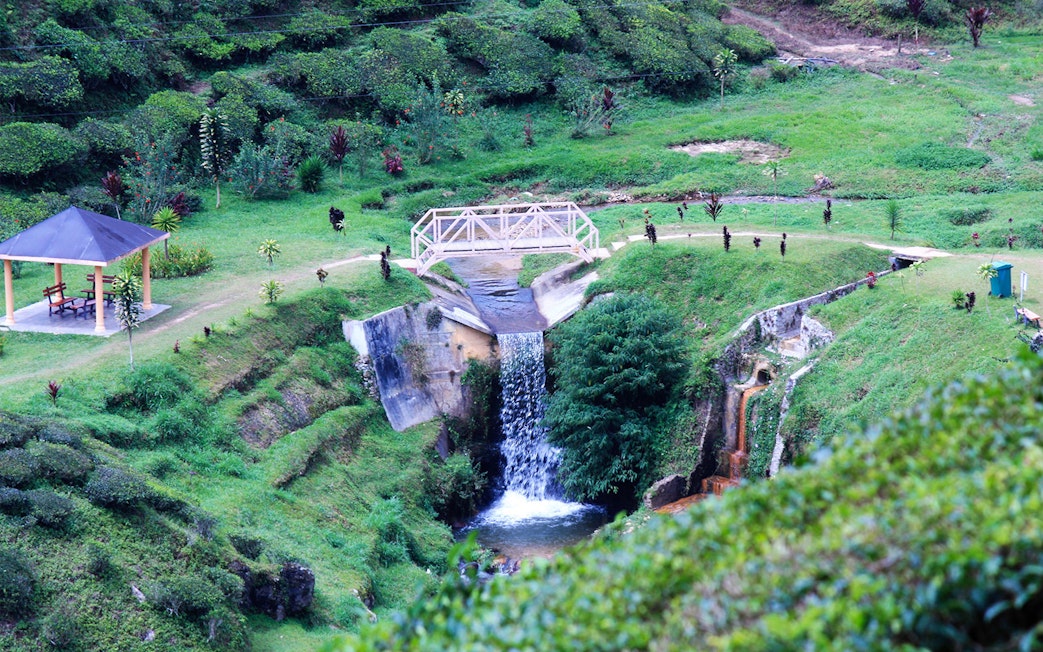 Waterfall and bridge in Cameron Highlands, Malaysia, surrounded by lush greenery.