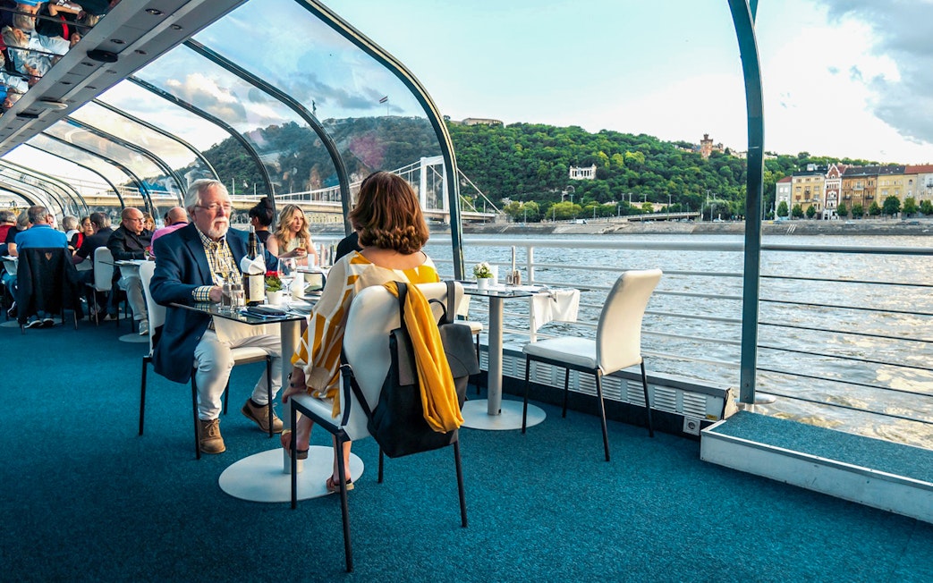 Guests dining on Budapest Candlelit Dinner Cruise with river and city views.