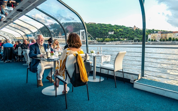 Guests dining on Budapest Candlelit Dinner Cruise with river and city views.