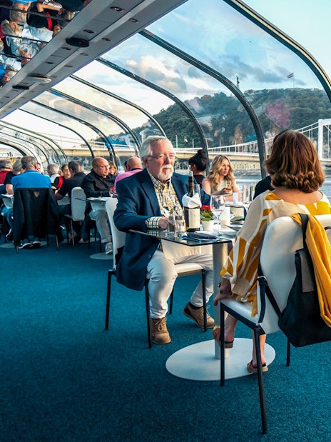 Guests dining on Budapest Candlelit Dinner Cruise with river and city views.