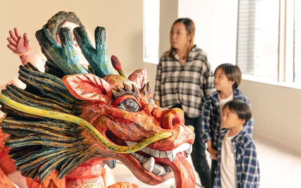 Visitors observing a colorful dragon sculpture at Koji Kinutani Tenku Art Museum.
