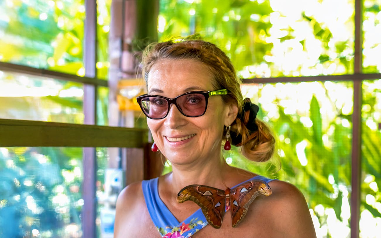 Visitor with butterfly at Kemenuh Butterfly Park, Bali.