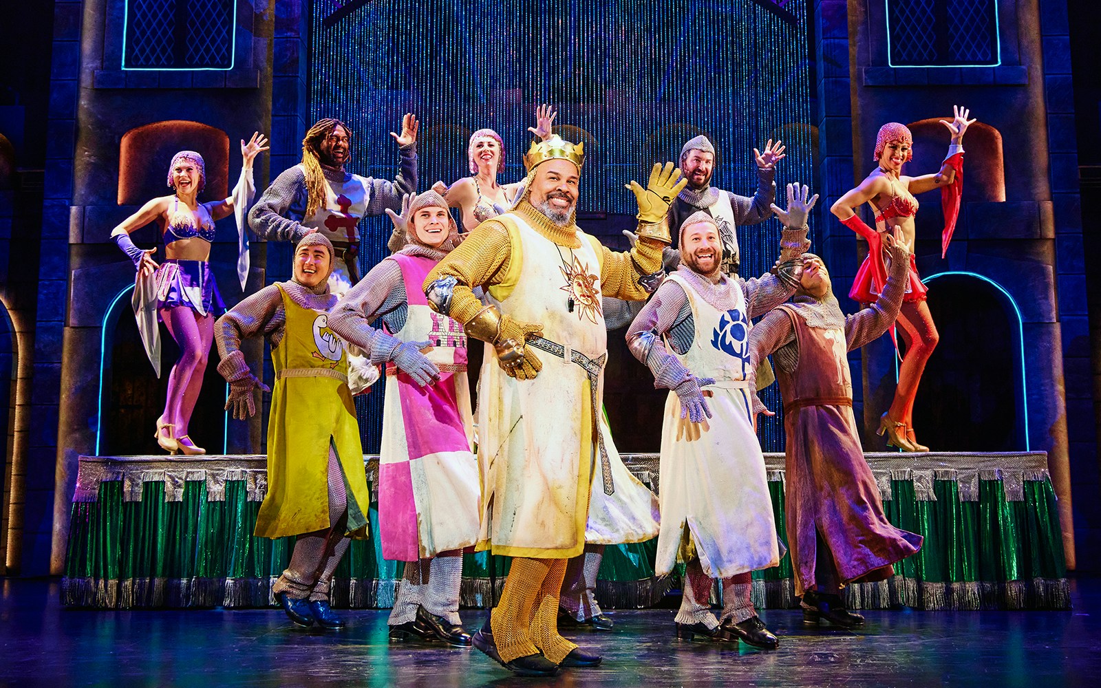 Cast of Spamalot performing on stage in medieval costumes.