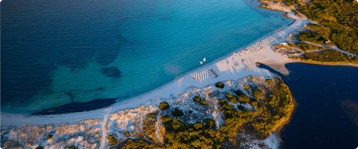 Aerial view of a beach near Sassari with turquoise waters and sunbathers.