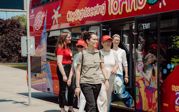 Tourists exiting City Sightseeing Turin hop-on hop-off bus.