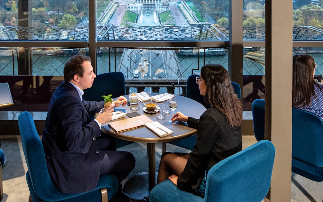 Couple dining at Madame Brasserie with view of Paris skyline.