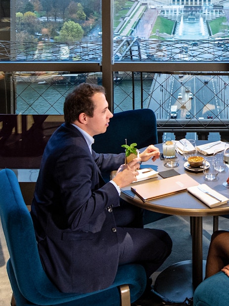 Couple dining at Madame Brasserie with view of Paris skyline.