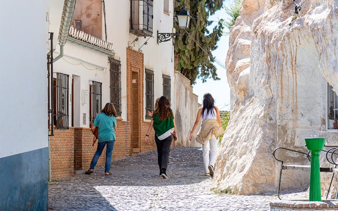 Walking tour in the Albaicín, Granada, with people exploring narrow cobblestone streets.